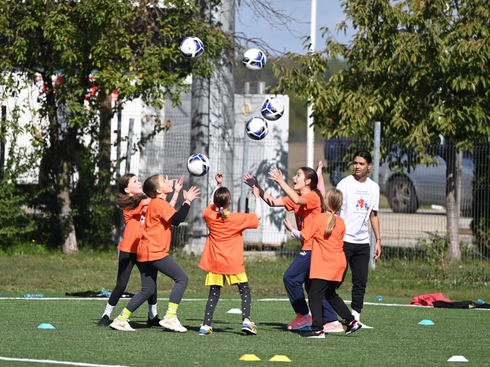 Girls training with footballs in the air