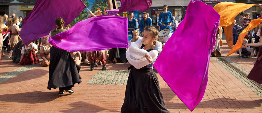 A girl waving colourful flags at an EEA Grants supported cultural event