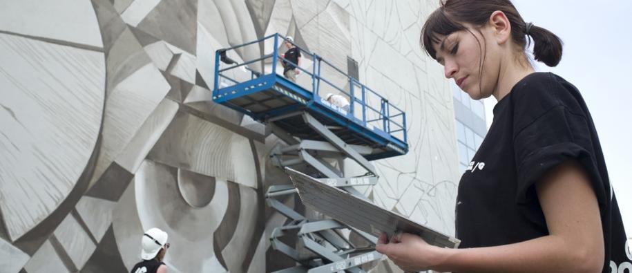 Young woman working and painting a mural